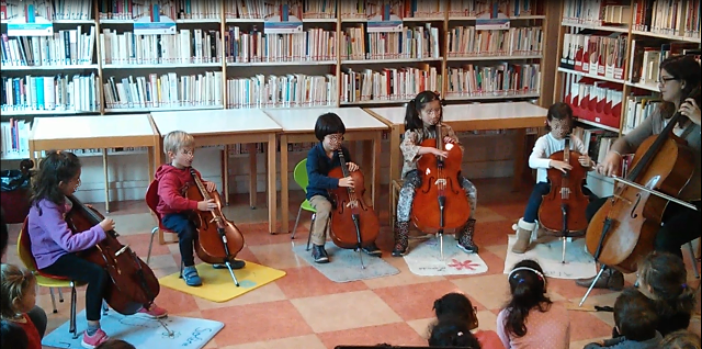 Children playing the celloin front of children classes in a library