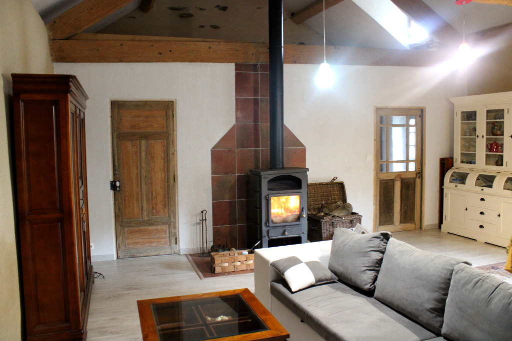View on the living room, with large convertible settee, small table and woodburner